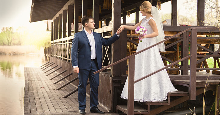 bride and groom holding hands on a pier