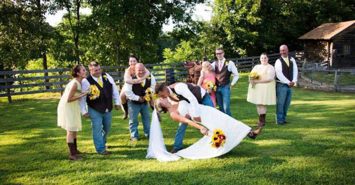 bride and groom kissing with their wedding party behind them