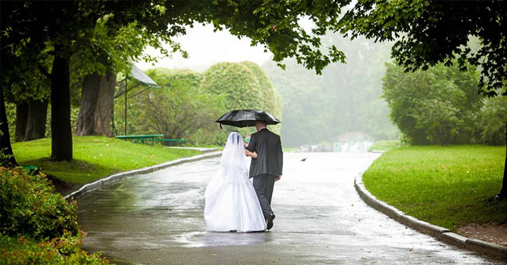 bride and groom walking under umbrella