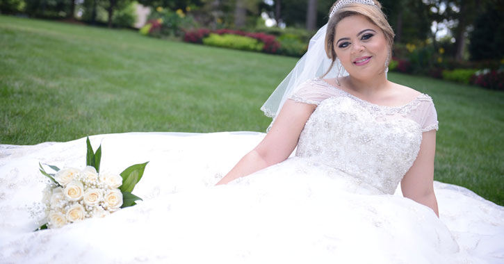 a bride laying on grass, dress spread out