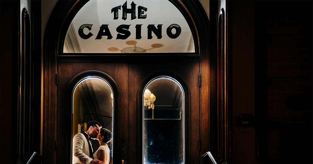A couple shares a kiss behind the Casino's glass doors.