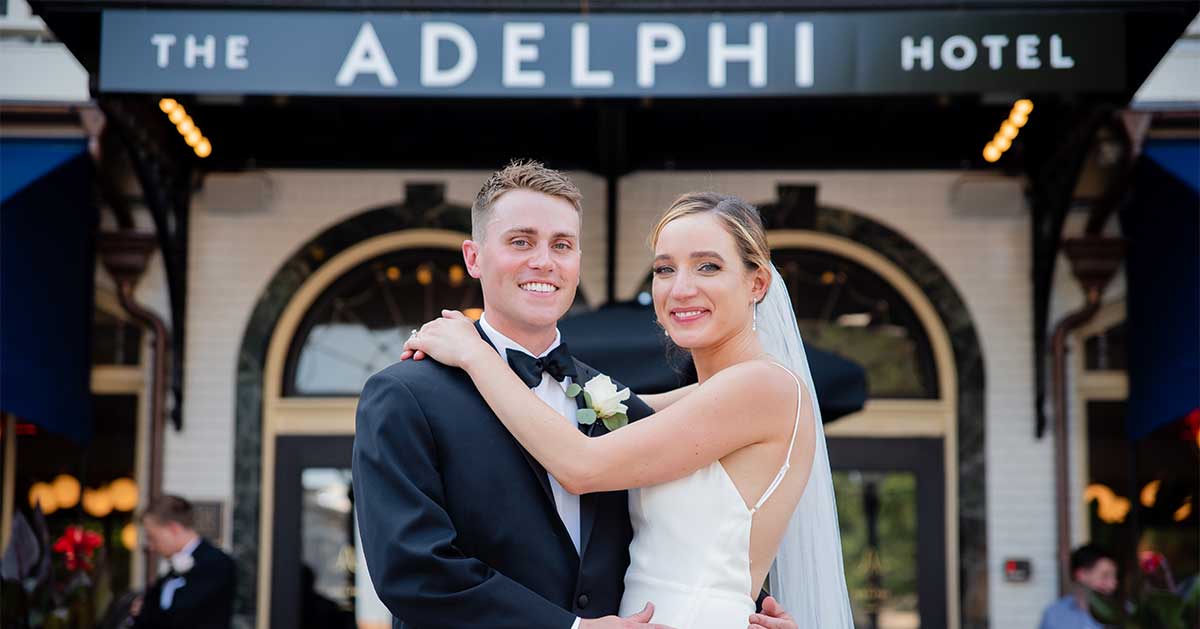 A couple poses in front of the Adelphi Hotel.