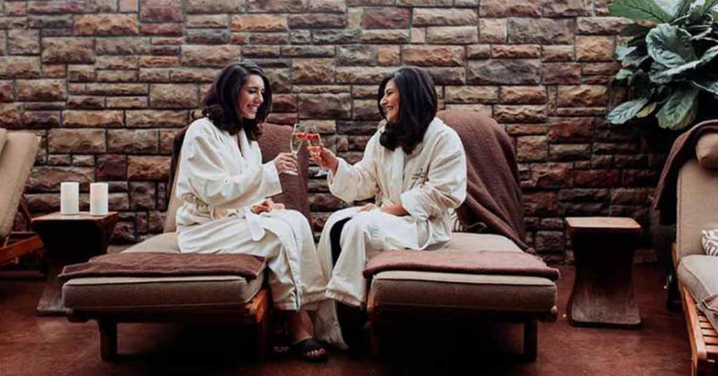 Women clink glasses while in a spa.