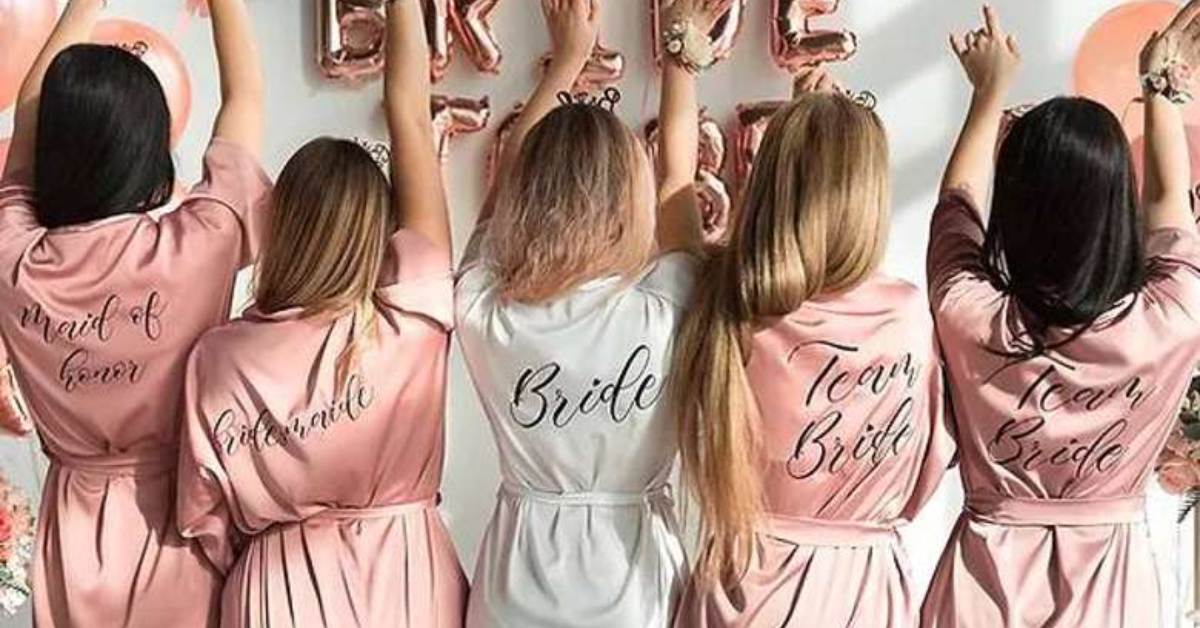 five women in bride and bridesmaids robes from the back