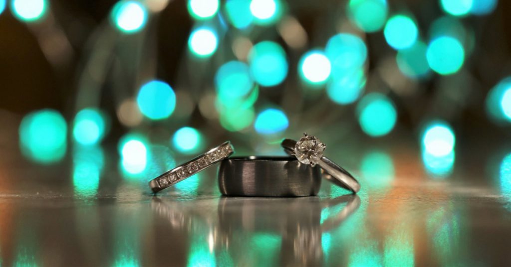 turquoise lights behind wedding rings