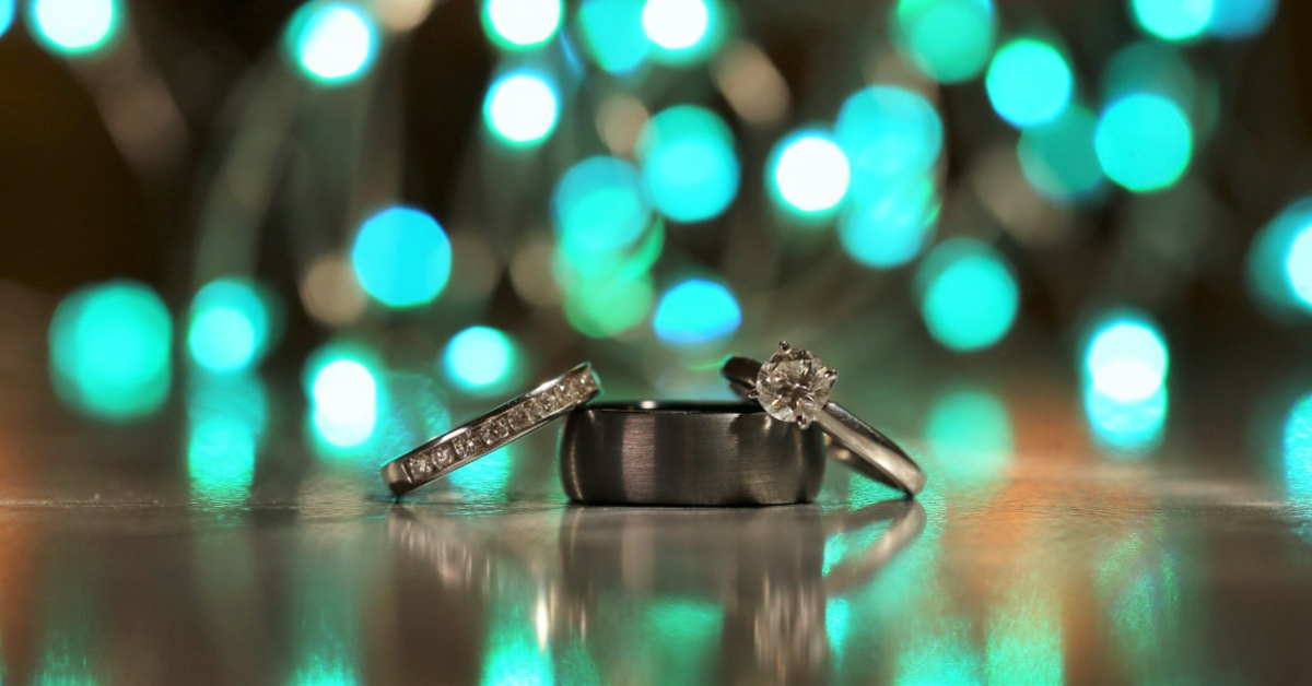 turquoise lights behind wedding rings