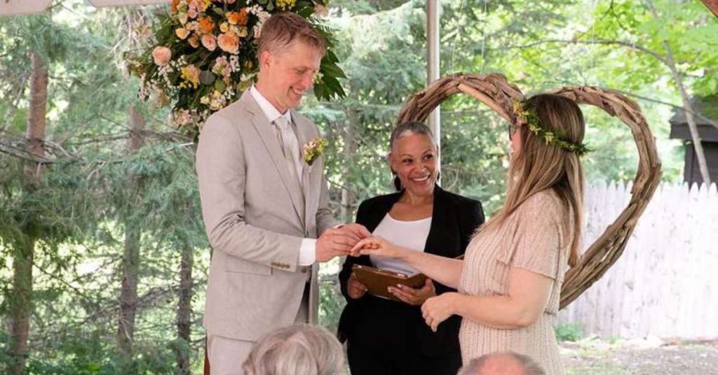 two people smiling as they get married by a smiling officiant