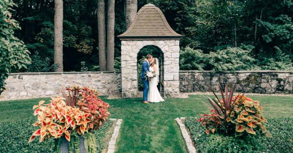 bride and groom kissing in front of a stone arch in a wall